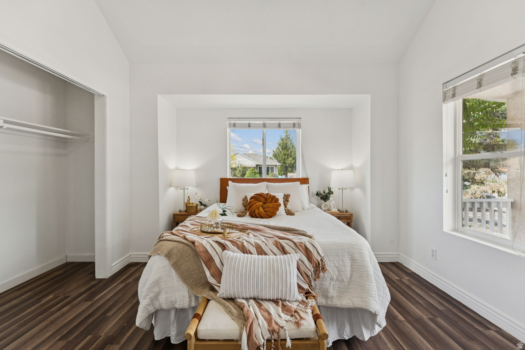 Bedroom with lofted ceiling, dark wood finished floors, and a closet