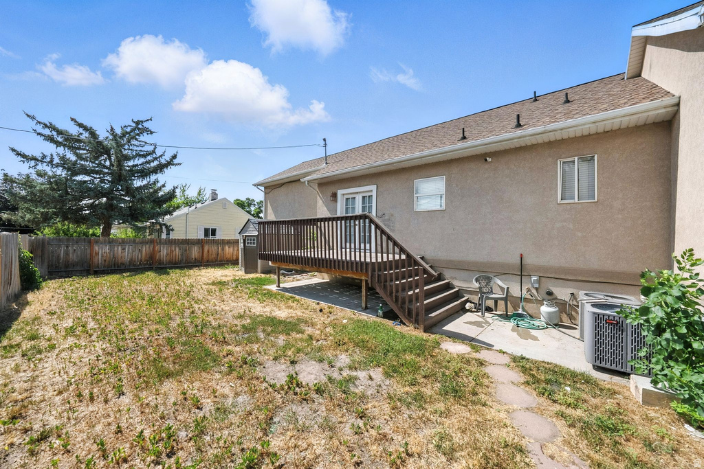 Rear view of house with a deck, stucco siding, a fenced backyard, a patio, and roof with shingles
