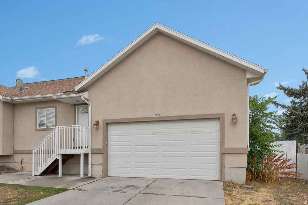 View of front facade with stucco siding, concrete driveway, and a garage