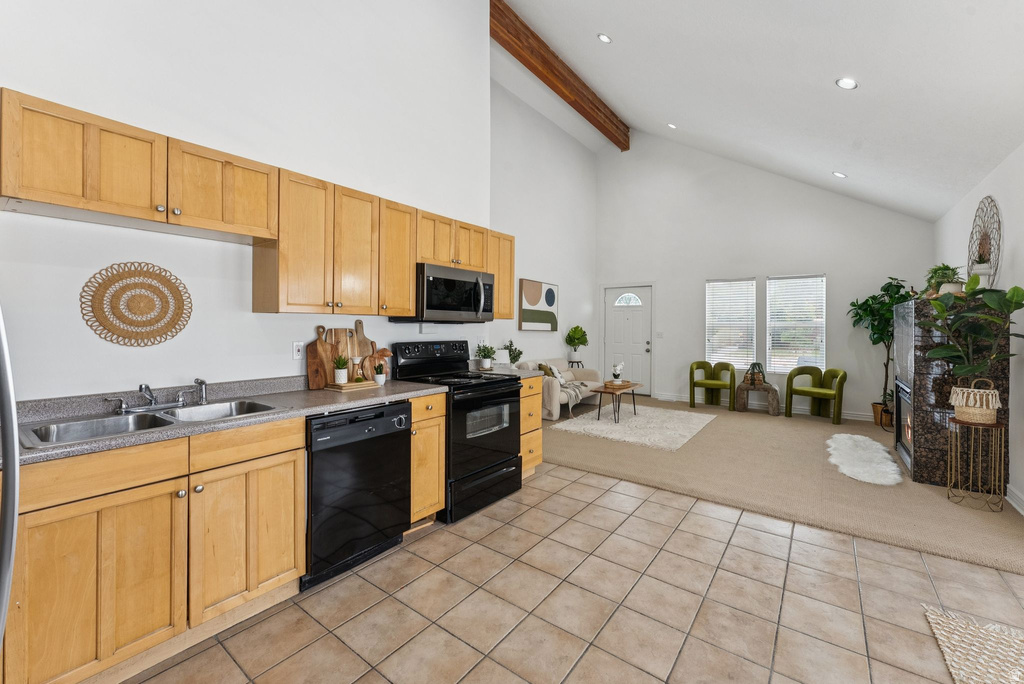Kitchen featuring black appliances, open floor plan, light carpet, vaulted ceiling, and light countertops