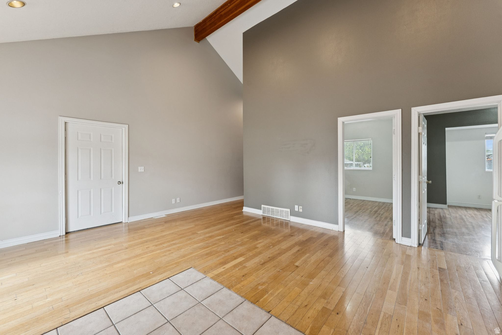 Unfurnished living room featuring light wood-type flooring and vaulted ceiling