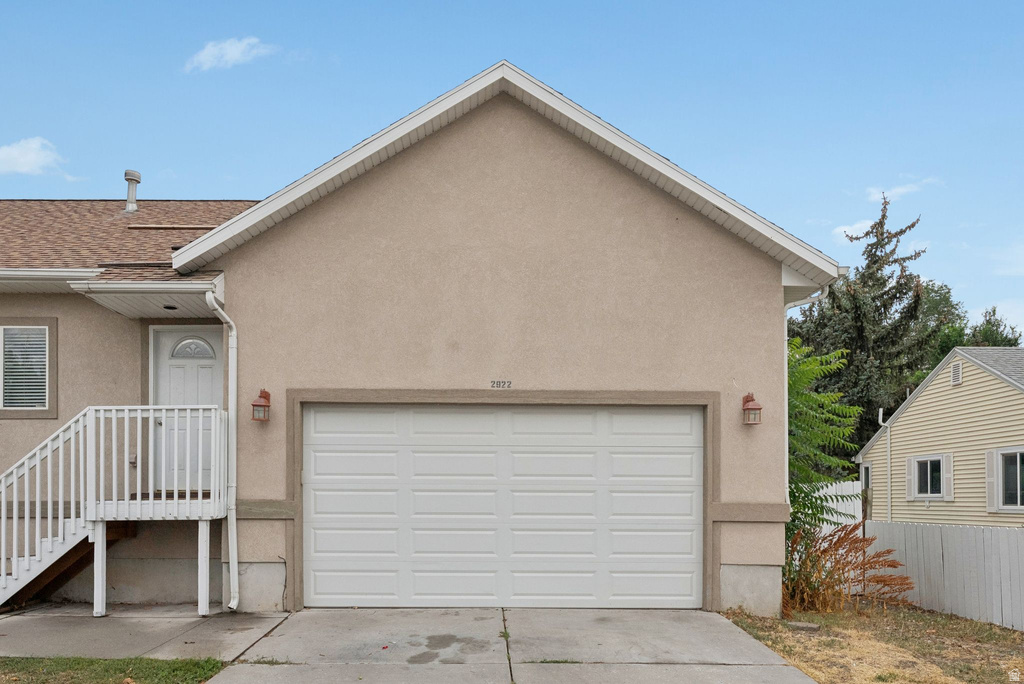View of front of property with stucco siding, concrete driveway, a garage, and a shingled roof