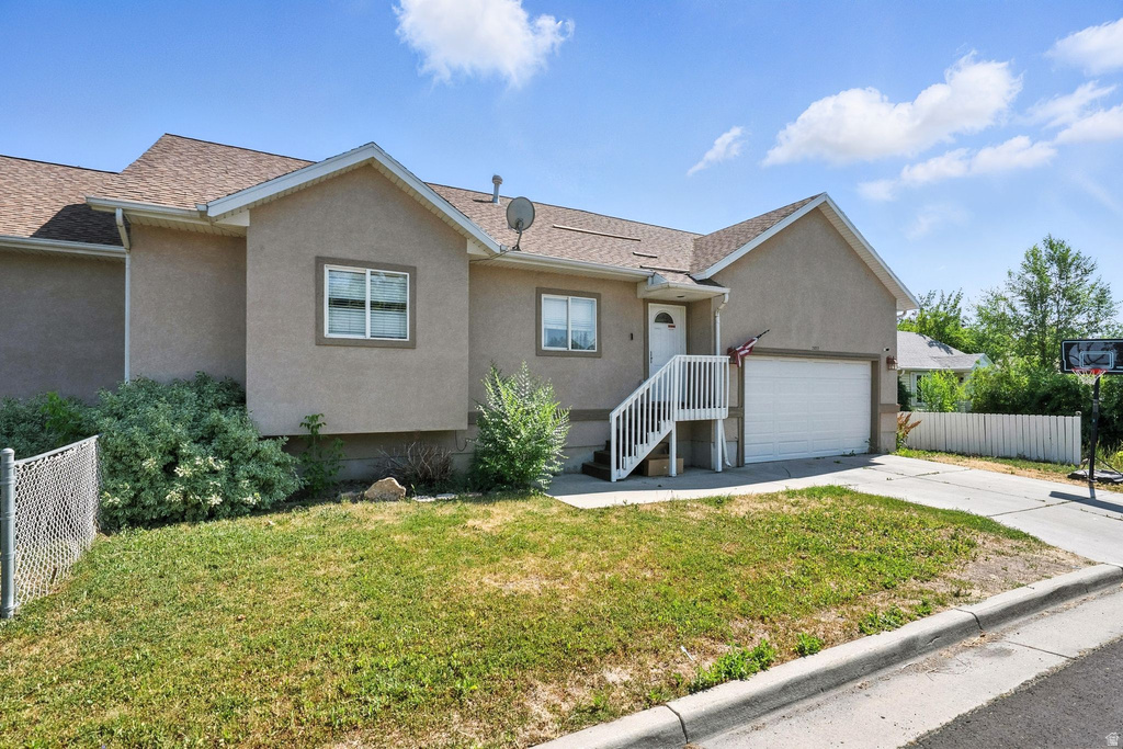 Single story home with stucco siding, driveway, a shingled roof, and an attached garage