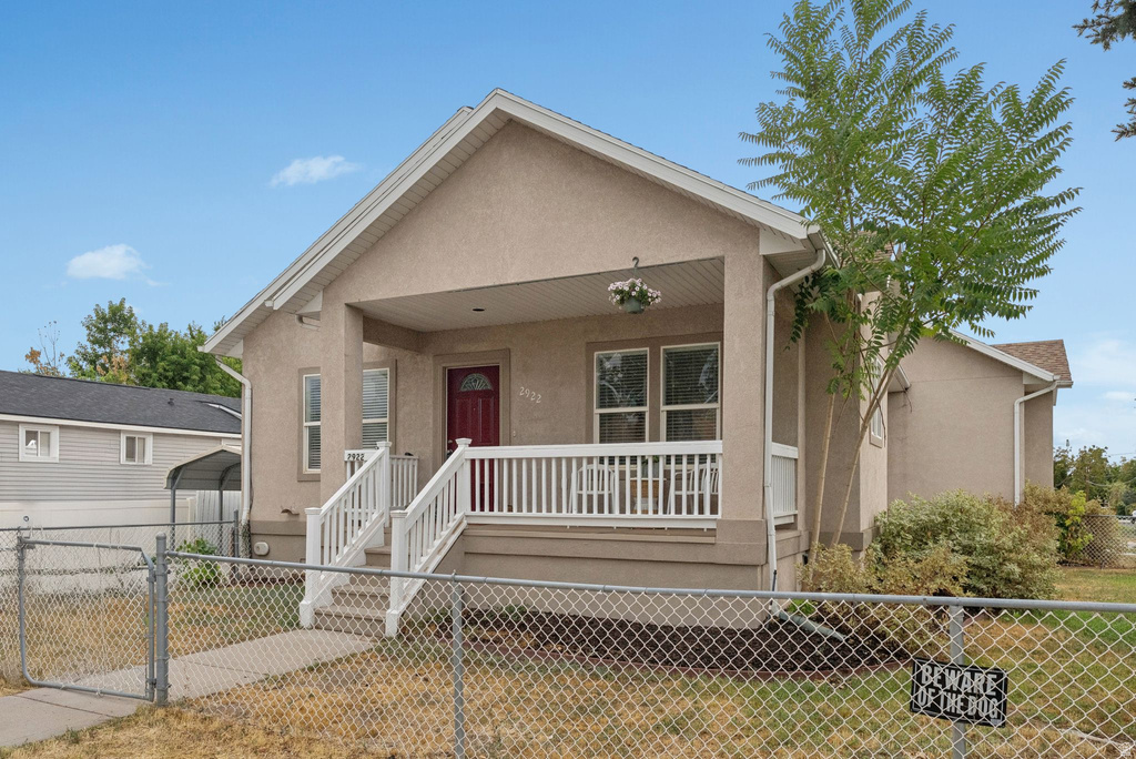 View of front of house with covered porch, a gate, and stucco siding