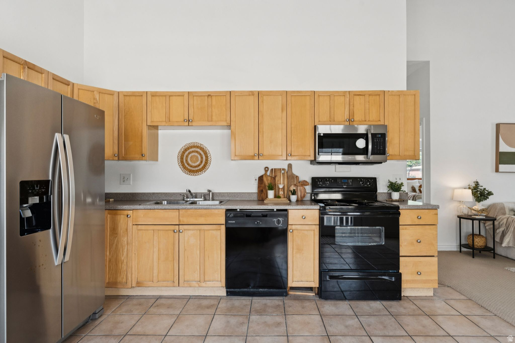 Kitchen with black appliances, a high ceiling, and light tile patterned flooring