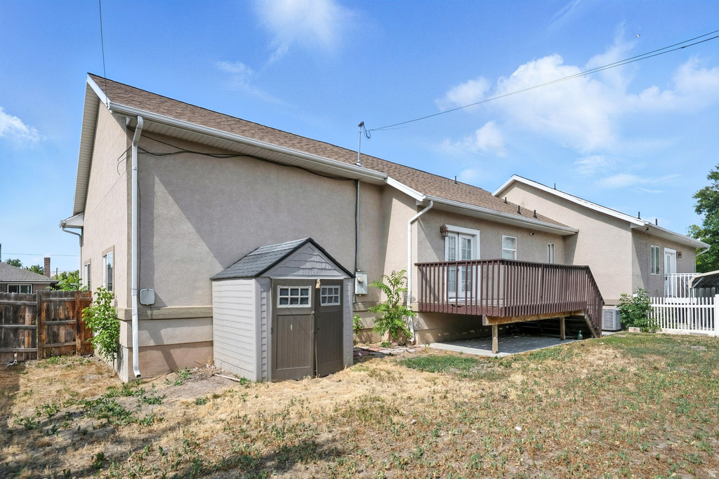 Rear view of house with a shed, a wooden deck, and stucco siding