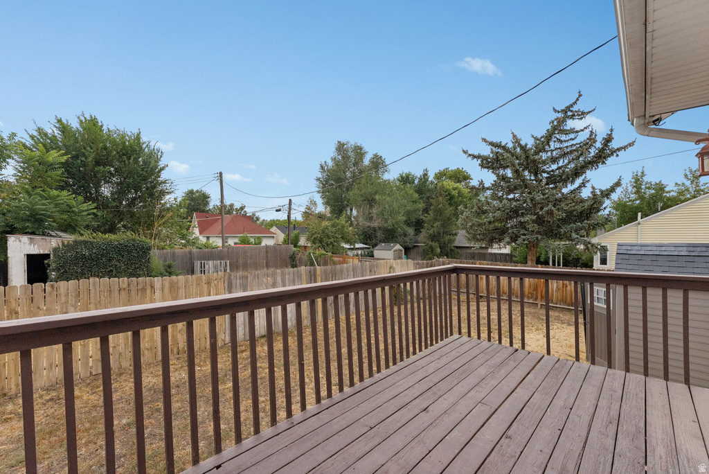 Wooden terrace featuring a fenced backyard and a shed