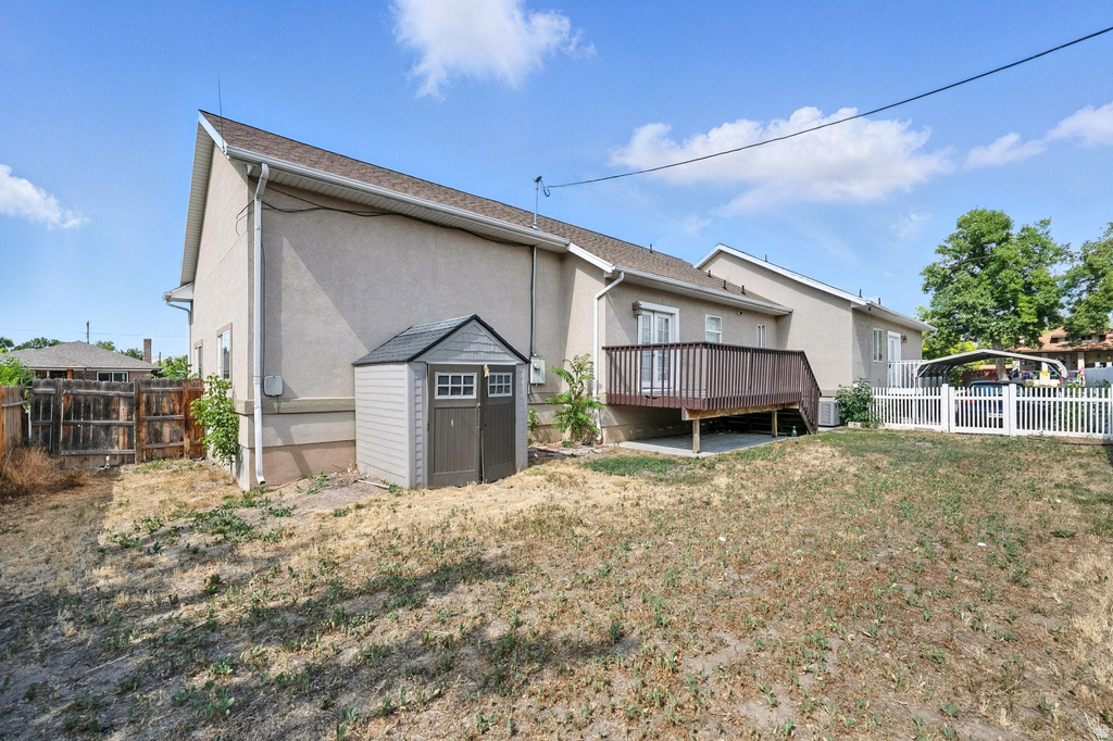 Back of house featuring a fenced backyard, a shed, a deck, and stucco siding