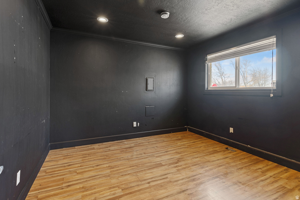 Unfurnished room with wood finished floors, recessed lighting, crown molding, and a textured ceiling
