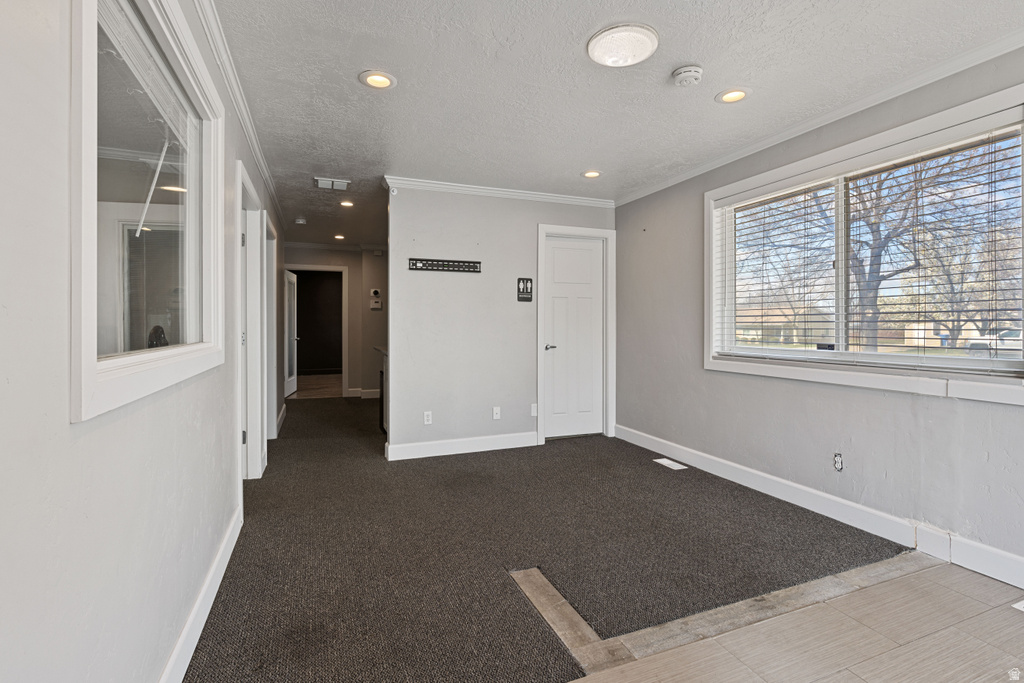 Carpeted empty room featuring a textured ceiling, recessed lighting, crown molding, and a smoke detector