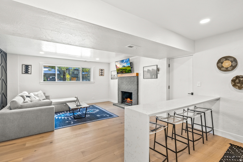 Living room with light wood-type flooring, a fireplace, and recessed lighting