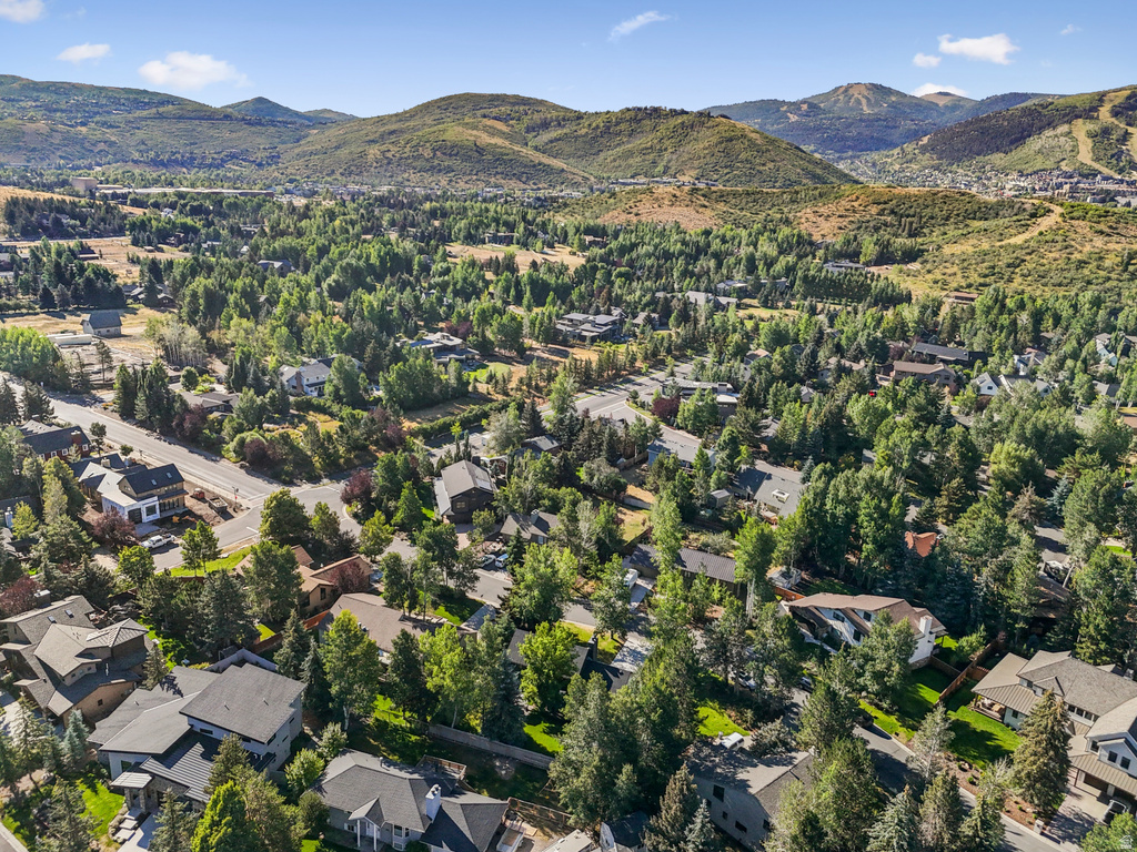 Aerial view of property and surrounding area featuring mountains and nearby suburban area