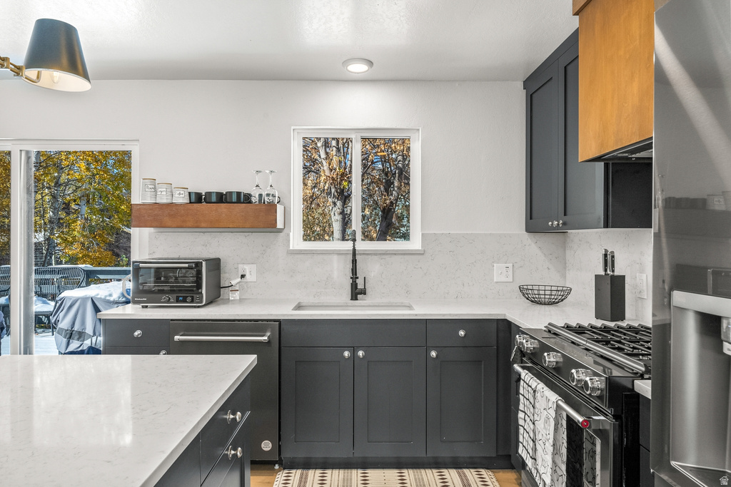 Kitchen with light stone counters, stainless steel appliances, backsplash, and open shelves