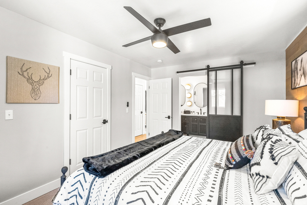 Bedroom with a ceiling fan, ensuite bath, and carpet flooring
