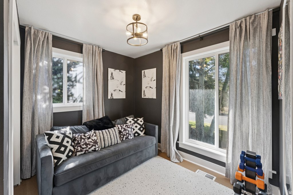 Living area with healthy amount of natural light, wood finished floors, and suspended lighting