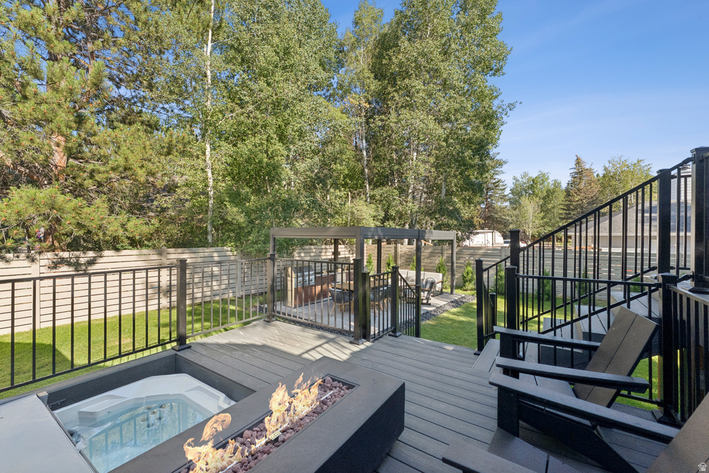Wooden terrace featuring an outdoor fire pit and a fenced backyard