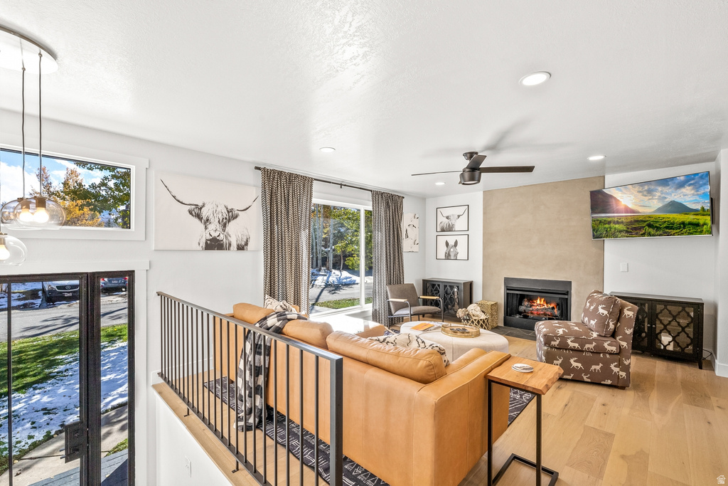 Living area with light wood finished floors, a large fireplace, a ceiling fan, and recessed lighting