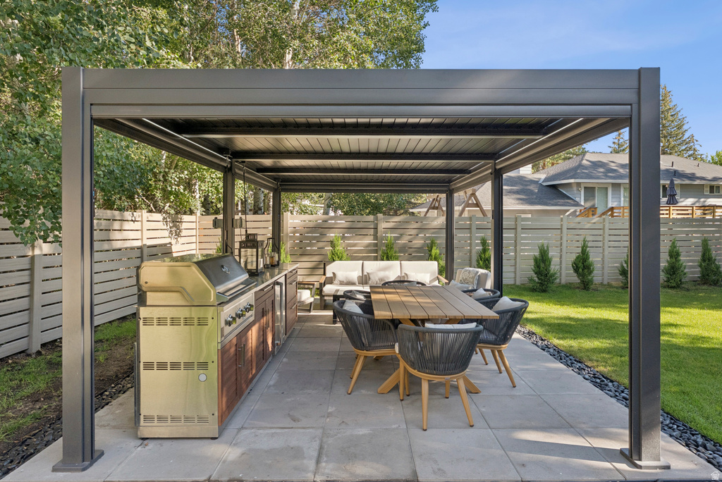 Fenced backyard with an outdoor kitchen, a patio area, and an outdoor living / dining area