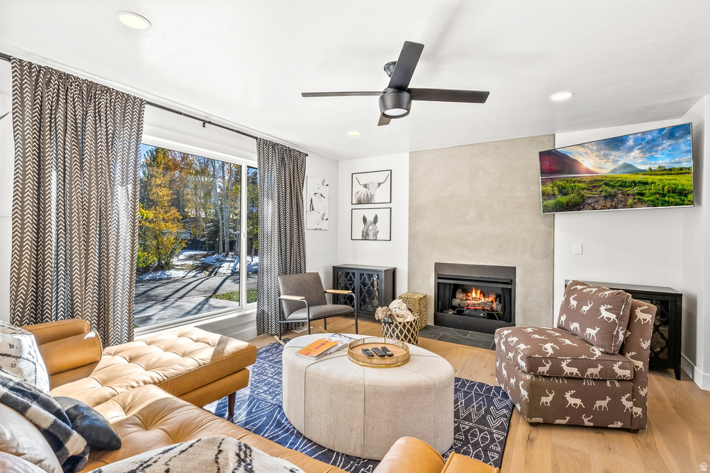 Living room with wood finished floors, a fireplace, ceiling fan, and recessed lighting