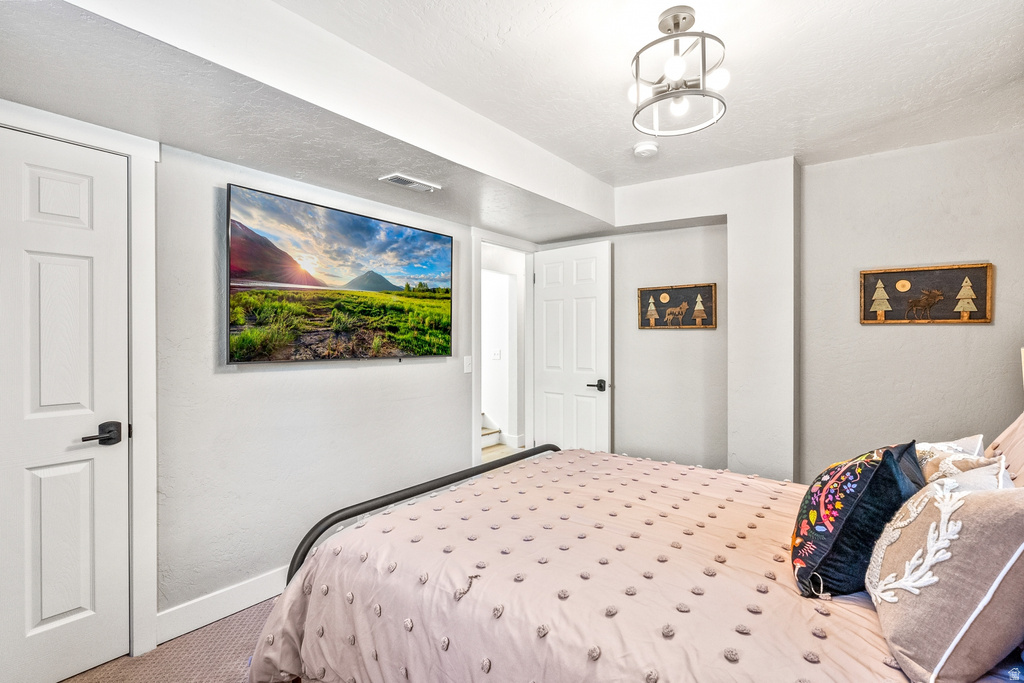 Bedroom with carpet floors, a textured wall, and a textured ceiling