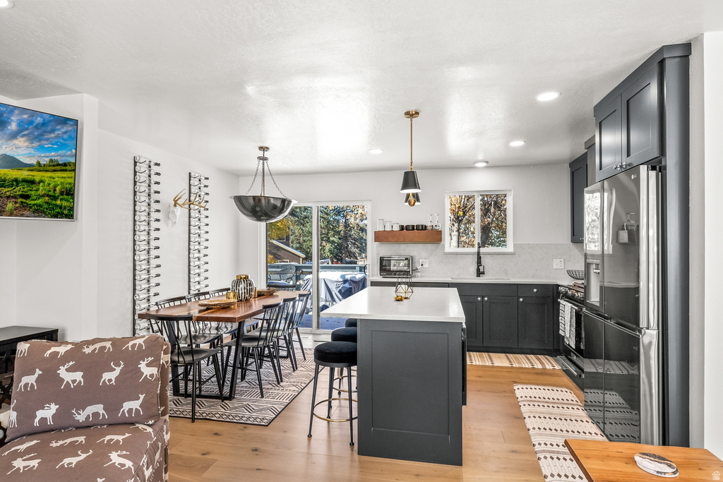 Kitchen with a kitchen island, light wood finished floors, decorative light fixtures, and a breakfast bar area