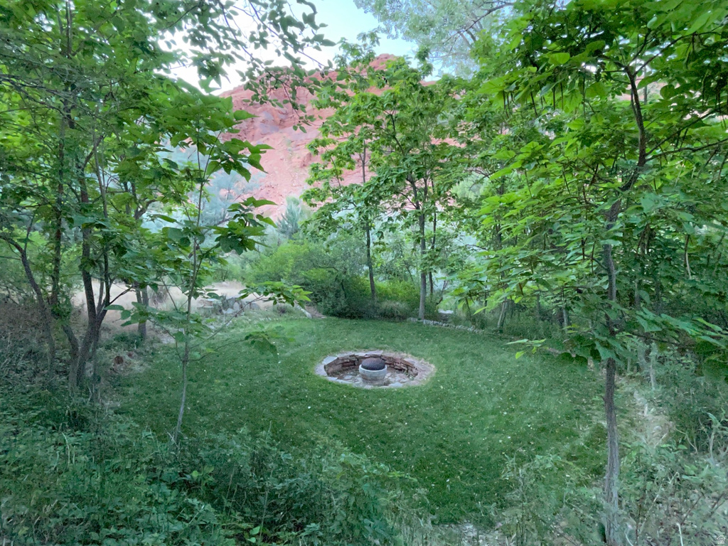 View of grassy yard with an outdoor fire pit