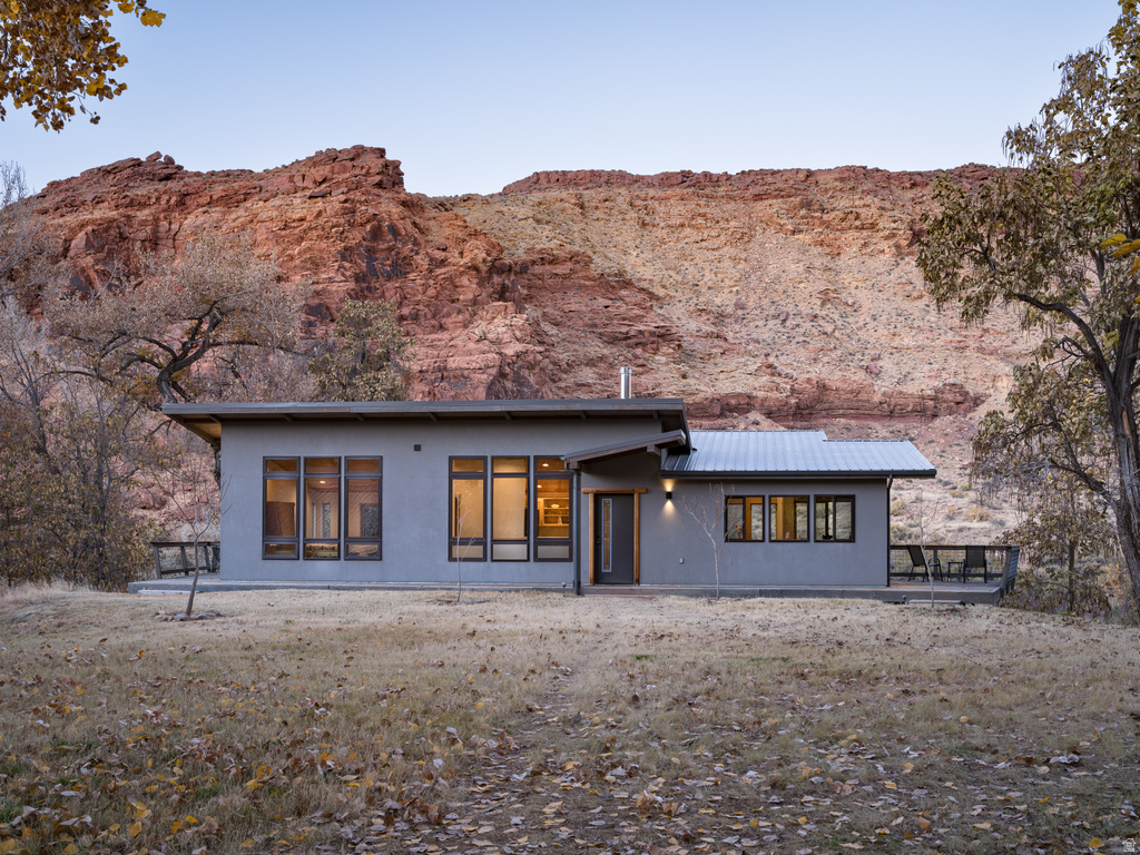 Rear view of property featuring a patio, a mountain view, stucco siding, and a metal roof