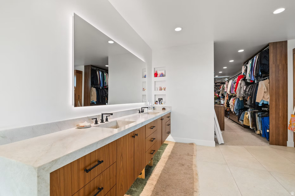 Full bath with a walk in closet, double vanity, recessed lighting, and light tile patterned flooring
