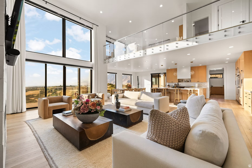 Living area with light wood finished floors, a high ceiling, and recessed lighting
