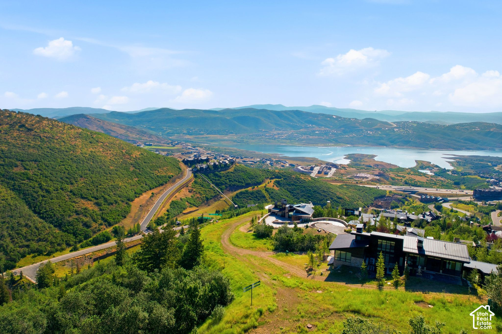 Expansive aerial perspective showcasing a mountainous terrain, a large body of water, and residential structures with modern architectural elements