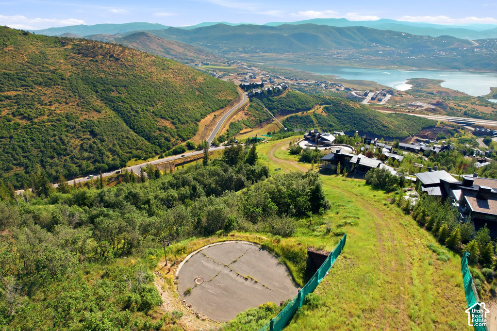 Mountainous terrain with expansive green hillsides, a winding road, and distant body of water
