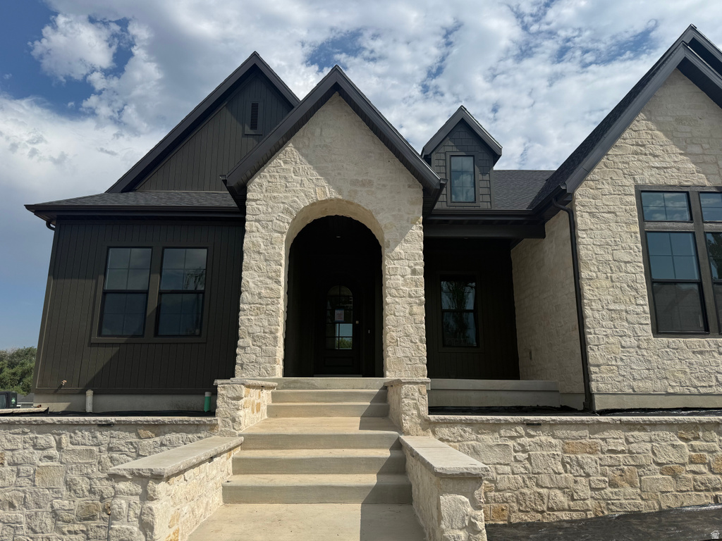 Stone and vertical siding exterior with a prominent arched entry