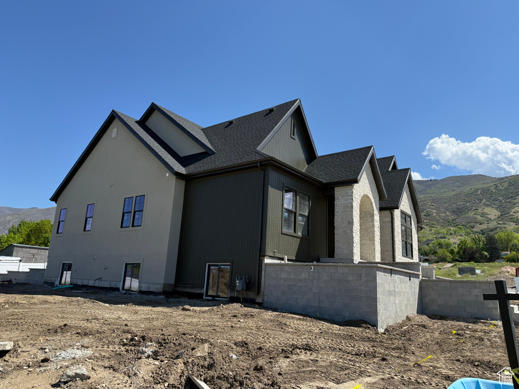 Modern exterior featuring a dark shingles roof, light stucco, and vertical dark siding