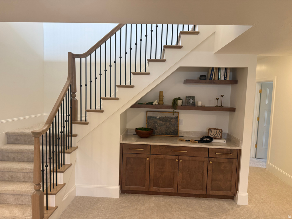 Staircase featuring wood handrails, black iron balusters, and carpeted treads
