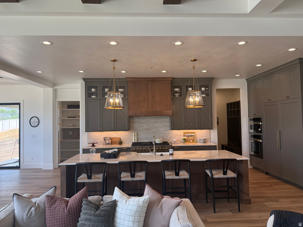 Gourmet kitchen with two-tone cabinetry, a large central island with seating, integrated appliances, and a wood-finish range hood