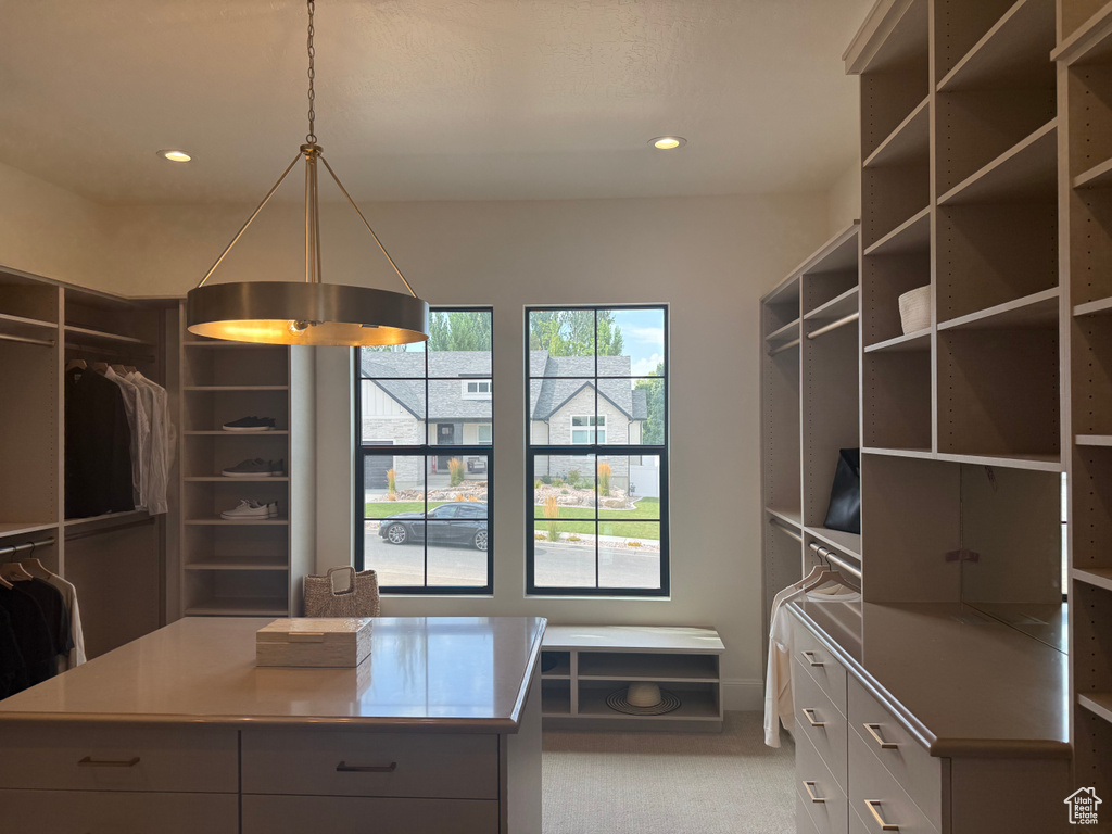 Spacious custom closet featuring extensive built-in shelving, a central island with storage, and integrated recessed lighting