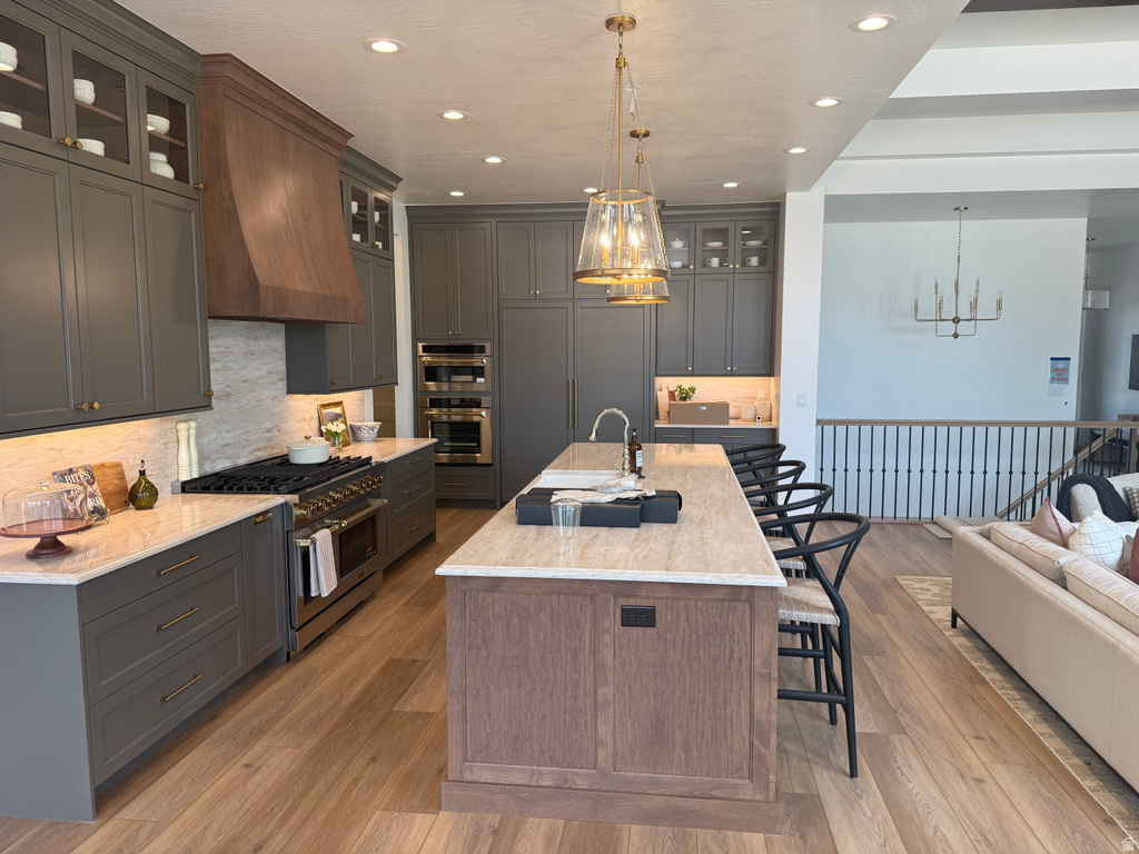 Gourmet kitchen featuring a wood-finish island with seating, pendant lighting, and light-toned countertops