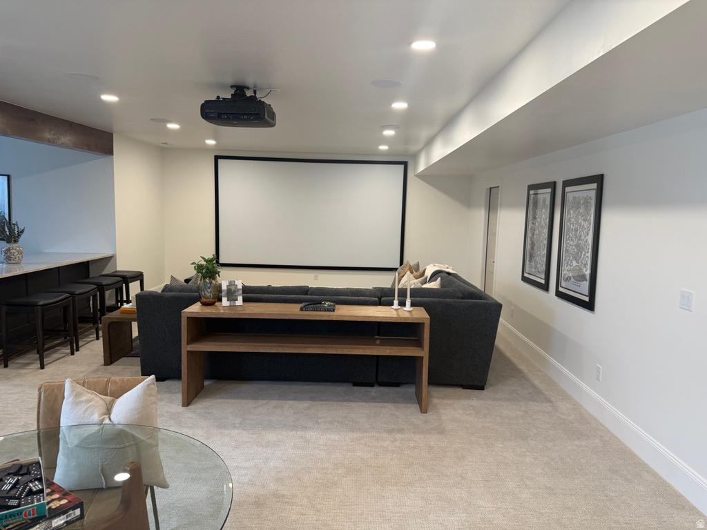 Integrated projector and large screen display, recessed lighting, neutral carpet flooring, built-in bar with dark cabinetry and light-toned countertop, and white baseboards
