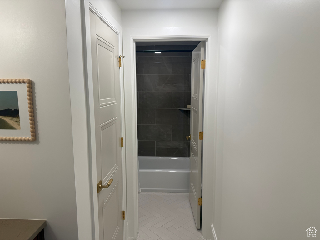 Bathroom featuring a white tub, dark grey tiled shower surround with a built-in niche, and white herringbone floor tile