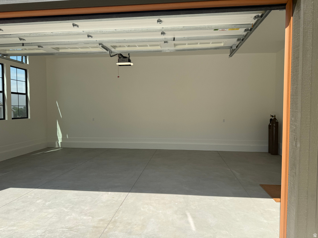 Spacious garage with light-toned concrete flooring, crisp white walls, and multiple grid-pattern windows providing natural illumination