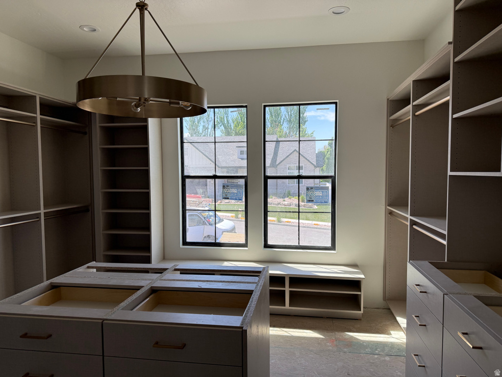 Spacious custom closet featuring extensive built-in shelving, hanging rods, and central island cabinetry