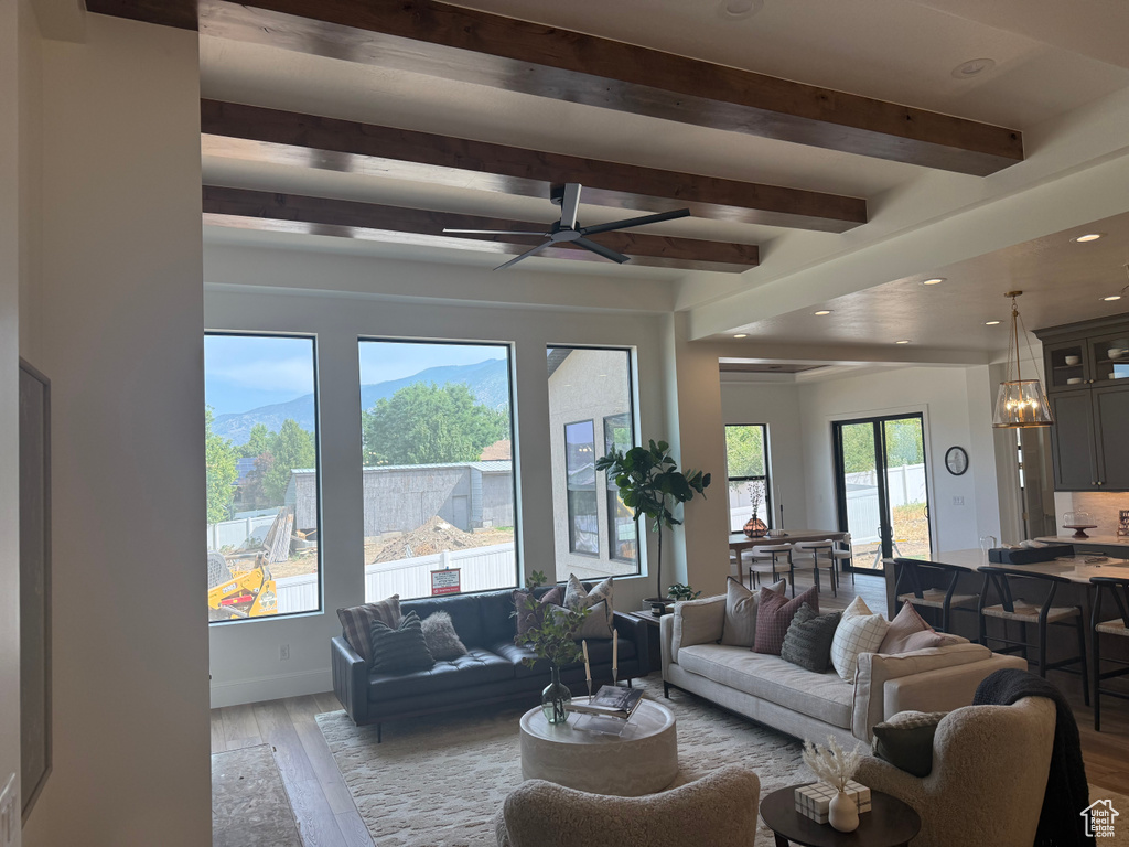 Spacious living area featuring large picture windows, wood-finish ceiling beams, and recessed lighting