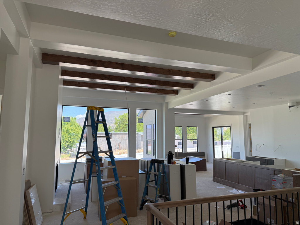 Expansive interior featuring exposed ceiling beams and recessed lighting