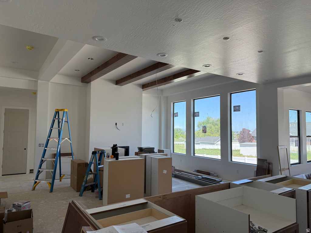 Spacious interior featuring recessed lighting, exposed ceiling beams, multiple large windows, and a partially installed cabinetry system