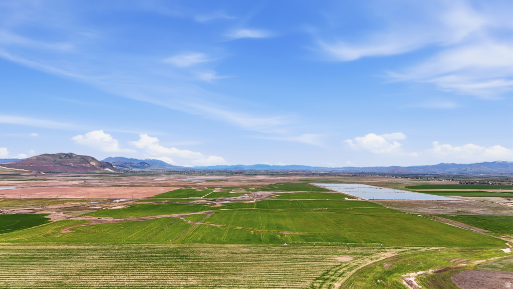 Expansive agricultural landscape featuring green fields, a significant body of water, and distant mountains