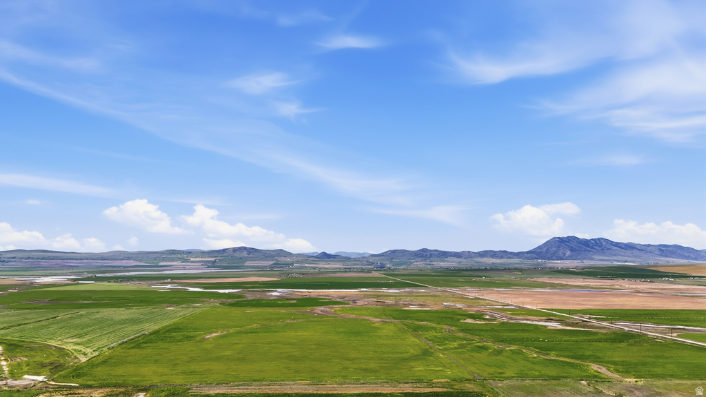 Expansive agricultural land featuring a mix of green fields and open terrain, with distant mountains under a clear sky