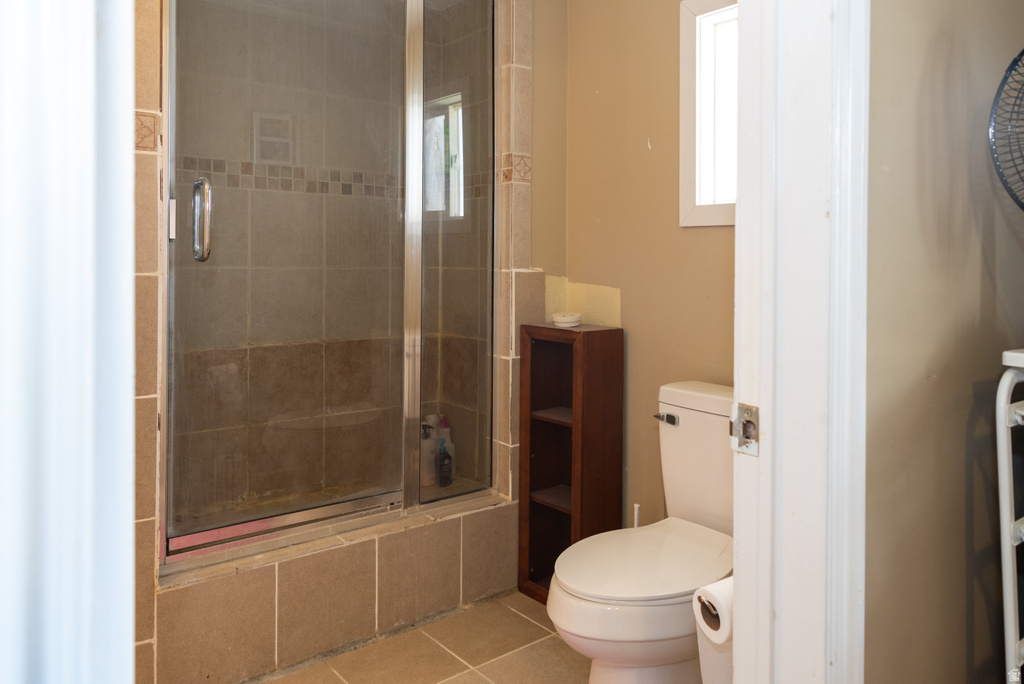 Bathroom with a shower stall and light tile patterned flooring