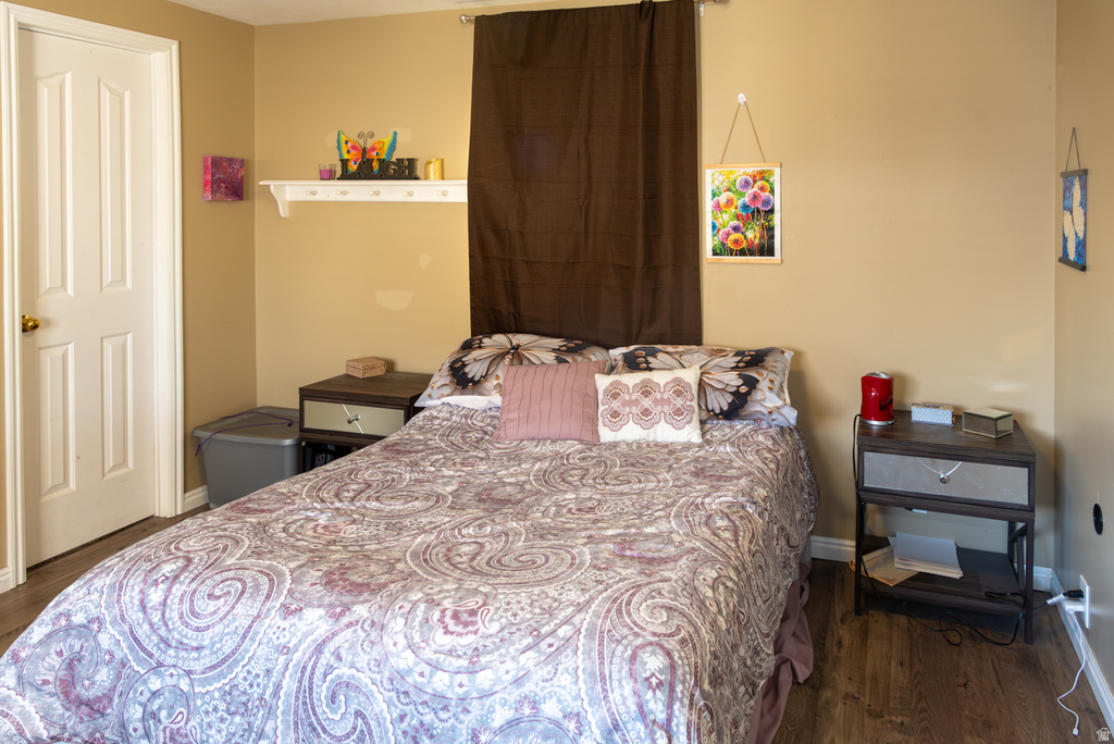 Bedroom featuring dark wood-style floors and baseboards