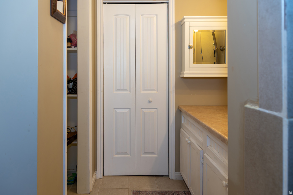 Bathroom featuring a closet, vanity, and light tile patterned floors