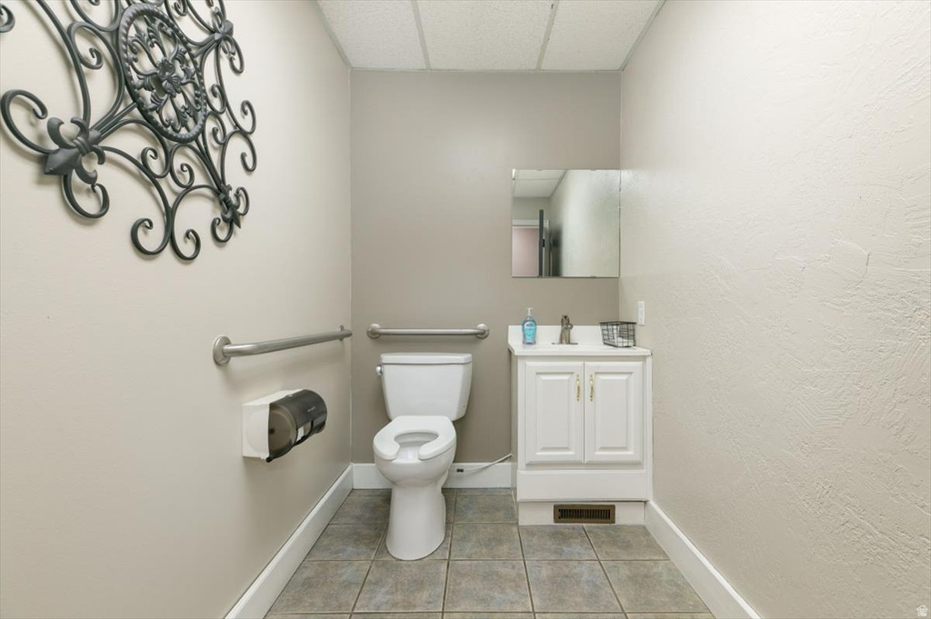 Bathroom with vanity, a drop ceiling, light tile patterned floors, and a textured wall